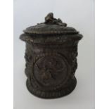 A cast metal vessel of cylindrical form with deep embossed relief depicting a classical battle