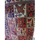 An eastern wool carpet with repeating squares pattern in red, blue and cream colourway