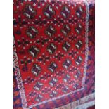 A red ground fringed wool rug with multimedallion centre in shades of deep red, cream, blue and