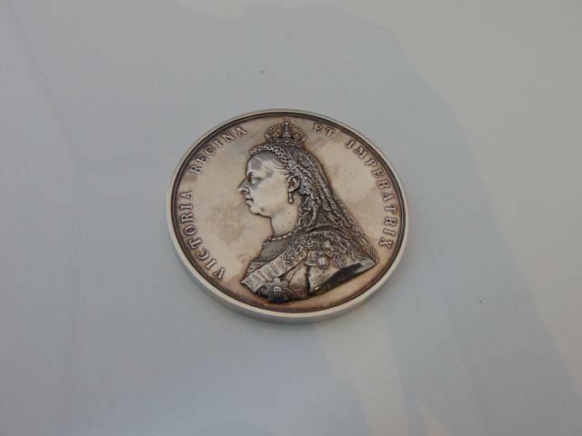 A heavy white metal Victorian commemorative medal with relief profile portrait of The Queen to one