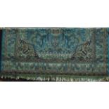 An extensive machine woven fringed wool rug with sky blue ground and central medallion in shades