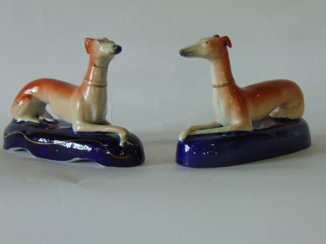 Two 19th century Staffordshire Pottery inkwells in the form of recumbent greyhounds raised on blue