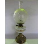 A Victorian oil lamp raised on an embossed brass foot supporting an opaque glass fount with Greek