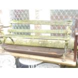 A Victorian three seat garden bench with weathered timber slatted seat and back raised on decorative
