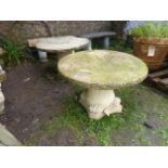 A pair of weathered contemporary cast composition stone low garden tables, the circular tops with