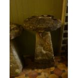 A weathered tall natural stone staddle stone and domed cap