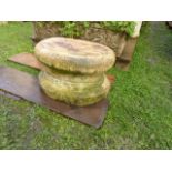 A weathered composition stone plinth of squat circular form together with a pair of composition