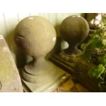 A pair of composition stone ball pillar caps with stepped square cut plinths