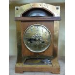 A late 19th century Arts & Crafts mantle clock in oak overlaid in brass with eight day striking
