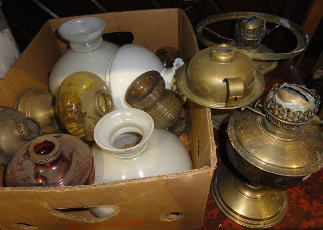 An assortment of vintage brass oil lamps and associated glass shades