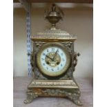 A Victorian brass mantle clock with cast detail, side handles and urn finial and enclosing and 8 day