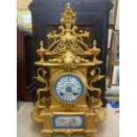 A 19th century mantle clock with gilded case, porcelain dial and panel showing a cherub enclosing an