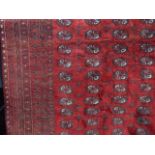 An Afghan red wool carpet with multi geometric detail within running borders principally in red