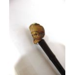 A slender bamboo walking cane terminating in an applied knop in the form of a carved male head