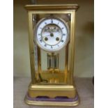 A 19th century brass cased four pane mantle clock with enamelled dial and visible escapement and