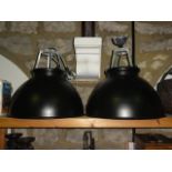 A pair of contemporary industrial ceiling lights of rounded form with blackened exterior and