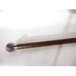 A tapering timber walking cane terminating in a white metal knop handle in the form of a golf ball