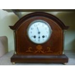 An inlaid Edwardian mahogany mantle clock with brass column supports and with eight day striking