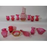 A quantity of cranberry glassware to include jugs with shaped rims, a model of fireside bellows with