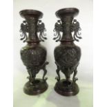 A pair of Chinese cast bronze vases of baluster form with drawn necks and flared rims, each