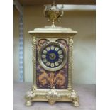 A brass cased mantle clock with cast detail set beneath an urn with eight day striking movement