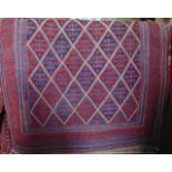 An Eastern red ground wool rug principally in a red and blue colourway within running borders 125