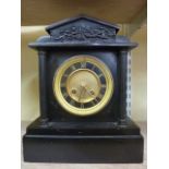 A Victorian black slate mantle clock in the classical style with reeded column supports enclosing an