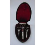 A leather shield shaped box enclosing three original pairs of bright cut steel scissors with