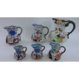 Six 19th century ironstone jugs of graduated size, all with floral detail and serpent handles,