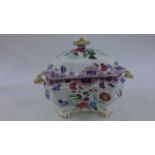 An ironstone tureen and cover with printed and infilled floral detail on scrolled supports