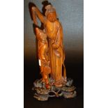 JAPANESE CARVED WOOD GROUP WITH A WOMAN HOLDING A DRAPE OVER AN ATTENDENT ON A STAND (h: 23.5 cm)
