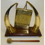 RECTANGULAR BRASS GONG SUSPENDED FROM BRASS HOOKS ATTACHED TO THE TIPS OF HORNS ON A WOODEN STAND