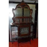 A LATE VICTORIAN CARVED MAHOGANY DISPLAY CABINET WITH A SHAPED ARCHED BEVELLED MIRROR BACK AND SHELF