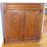A PITCH PINE ALCOVE CABINET WITH A DRAWER AND TWO PANELLED DOORS (W: 120 cm)