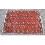 A BOKHARA PATTERN RUG, THE MADDER FIELD WITH TWO ROWS OF OCTAGONS AND STYLISED FLORAL DECORATION (