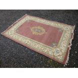 A KAYAM RUG, PINK FIELD WITH A CENTRAL FLORAL MEDALLION, SPANDRELS SURROUNDED BY A FLORAL BORDER (