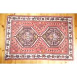 SHIRAZ RUG WITH TWO DIAMOND SHAPED LOZENGES IN THE CENTRE ON A RED FIELD              (153 cm x