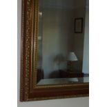 RECTANGULAR BEVELLED GLASS MIRROR IN A GILT PAINTED WOODEN FRAME (76 cm x 53 cm)