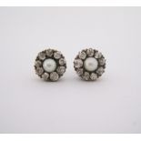 A PAIR OF DIAMOND AND PEARL EAR STUDS each of flowerhead form, centred with a pearl measuring