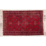 AN AFGHAN CARPET, MODERN the red field with overall guls depicted in blue, ivory, orange and red