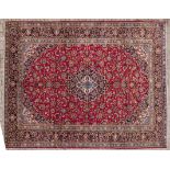 A KESHAN CARPET, PERSIA, MODERN the red field with a dark indigo blue and ivory floral medallion,