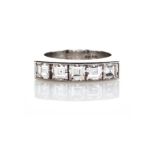 A DIAMOND RING channel set to the centre with a row of five carré-cut diamonds weighing