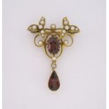 A GARNET AND SEED PEARL BROOCH designed as stylised scrolling foliage claw set with an oval mixed-