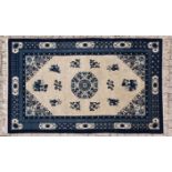A CHINESE CARPET, MODERN the ivory field with round blue floral medallion and spandrels, scattered