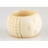 A large ivory bangle carved with a stylised face and a band of carved chequerboard design Not