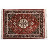 A Qum Silk Rug, Persia, Modern, the red field with an ivory and blue floral medallion, indigo blue