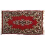 A Kirman Rug, Persia, Modern the red field with a multi-coloured floral medallion, blue spandrel.