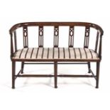 AN EDWARDIAN MAHOGANY AND UPHOLSTERED SETTEE the curved top rail above pierced and turned