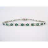 AN EMERALD AND DIAMOND BRACELET designed as a line of circular-cut emeralds weighing approximately