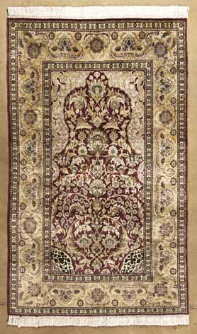 A HEREKE SILK PRAYER RUG,TURKEY,CIRCA 1970 the burgundy-red mehrab with an ascending design of